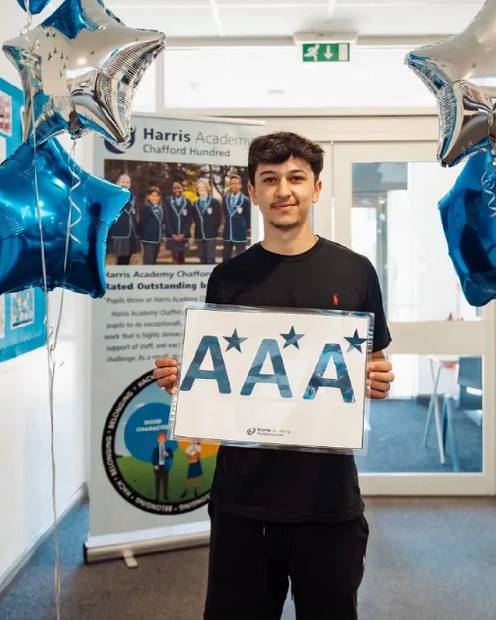 Ivan holding an A* A* A* sign on results day